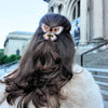 Person with styled hair featuring a decorative hair clip in front of a building