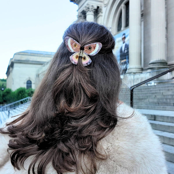 Person with styled hair featuring a decorative hair clip in front of a building
