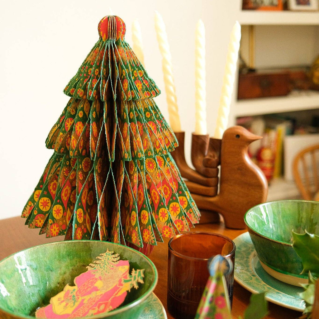 Decorative paper Christmas tree on a table with green bowls and a mug.