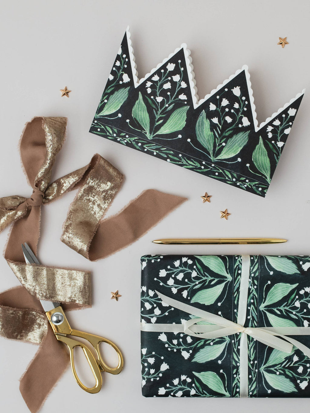 Floral-patterned gift wrap with ribbons and scissors on a light gray background