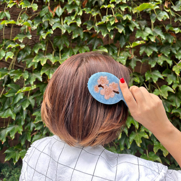 Person with a floral hair clip against a green ivy wall