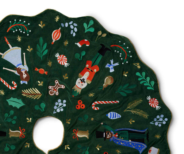 Decorative green tree skirt with embroidered festive designs on a white background