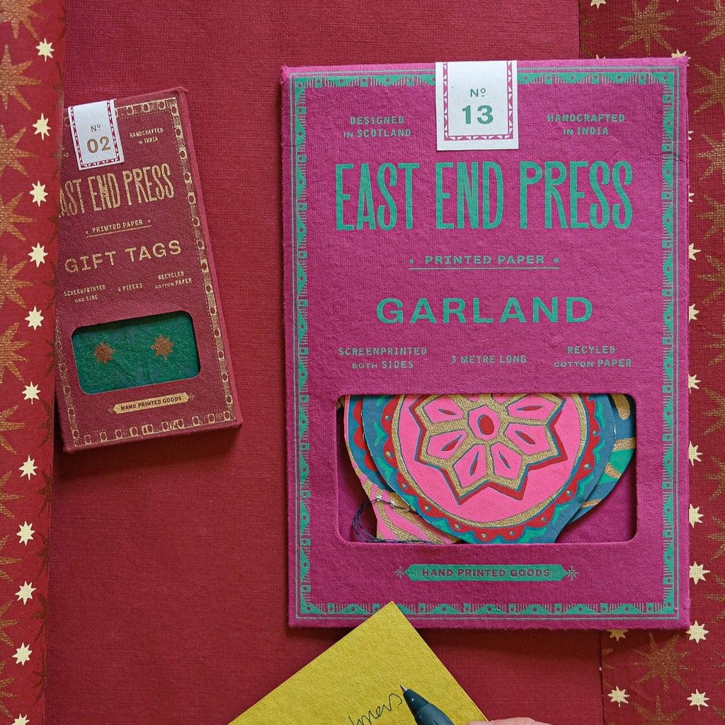 East End Press gift tags and garland on a red background with decorative elements.