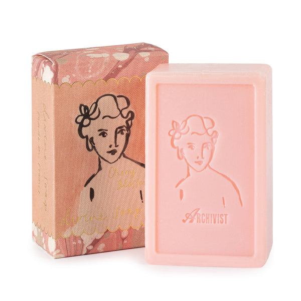 Pink soap bar and packaging with a woman's face design on a white background