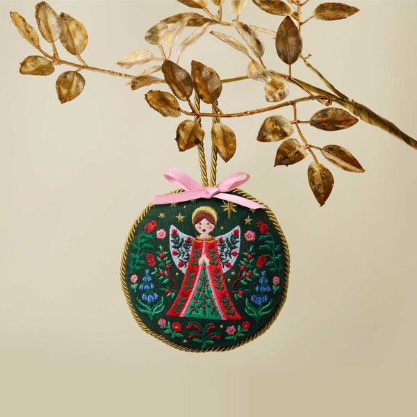 Decorative angel ornament with pink ribbon on a beige background