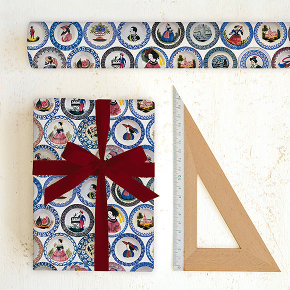 Gift wrapped in patterned paper with a red ribbon, next to a ruler on a white background