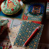 Decorative stationery items including a notebook, pen, and gift box on a colorful surface.