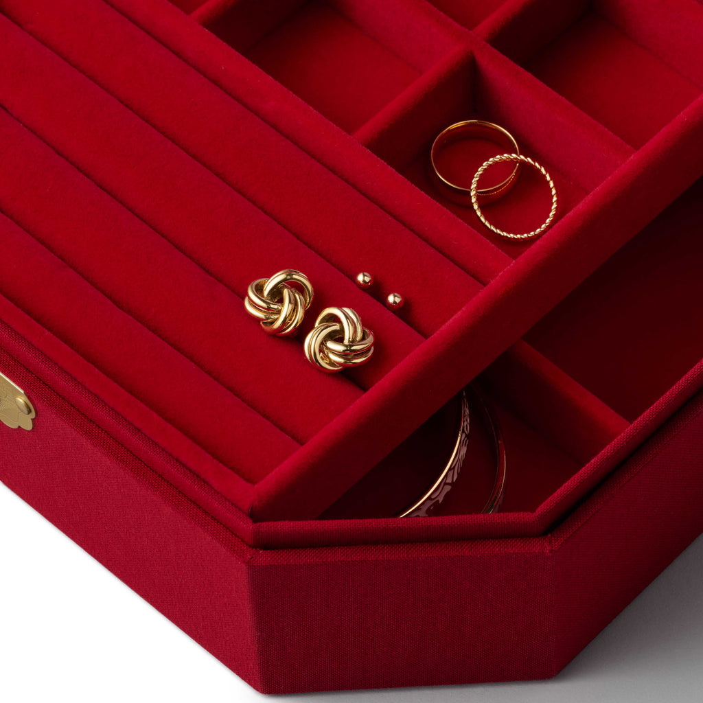 Red jewelry box with gold earrings and rings on a white background