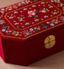 Red embroidered box with floral patterns and a gold clasp on a beige surface