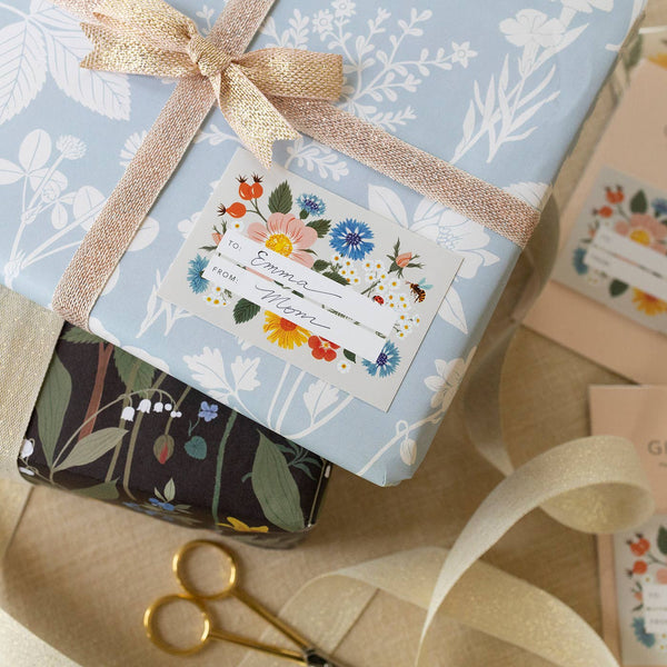 Gift box with floral design and ribbon, surrounded by more gift boxes and a pair of scissors.