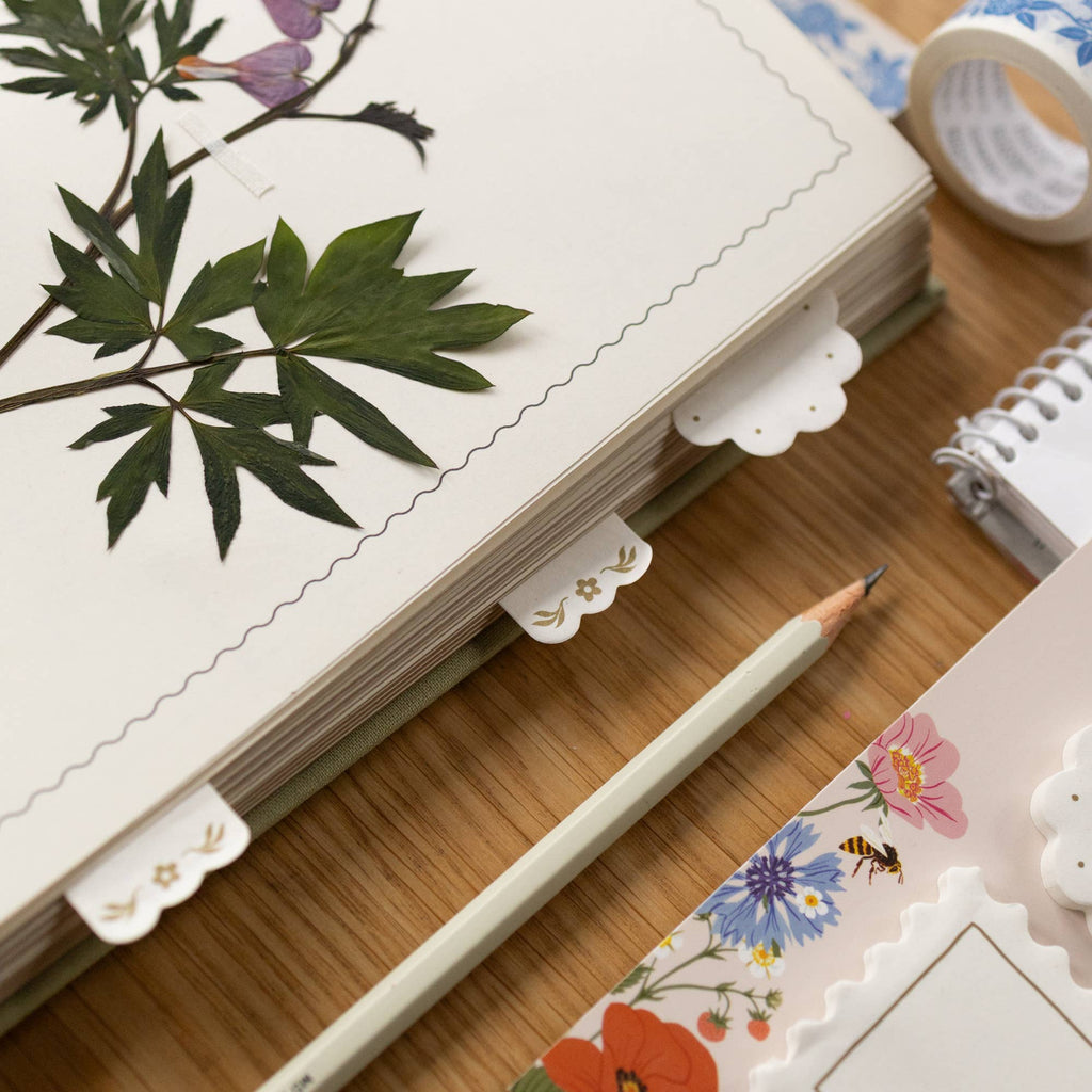 Notebook with floral and leaf designs on a wooden surface with a pencil.