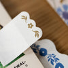 Close-up of a decorative card with floral designs on a wooden surface.