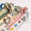 Assorted rolls of decorative tape with floral and patterned designs on a white background