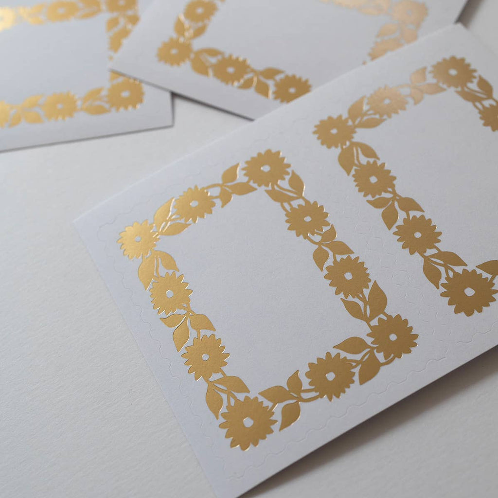 White cards with gold floral patterns on a light gray background