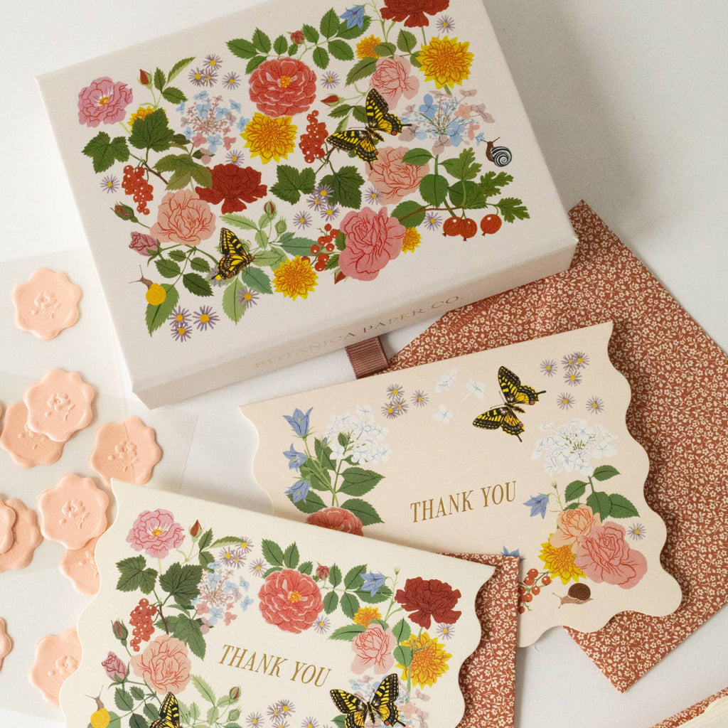 Floral-themed stationery set with 'Thank You' cards and a box on a textured surface.