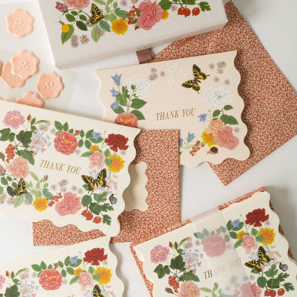 Floral and butterfly-themed cards with 'THANK YOU' text on a textured surface.