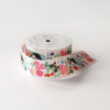 A roll of decorative ribbon with a colorful floral and butterfly pattern on a white spool, photographed on a clean white background.