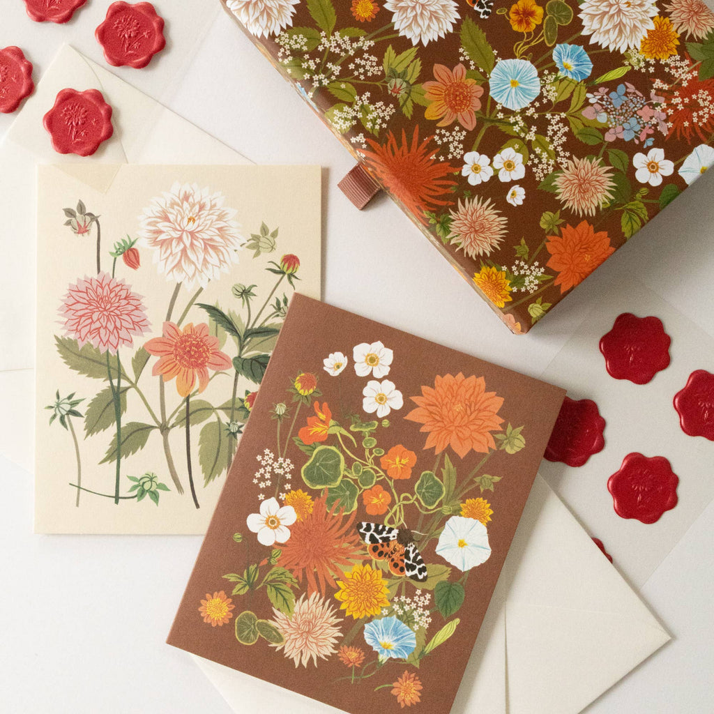Floral-patterned notebooks and envelopes on a white background