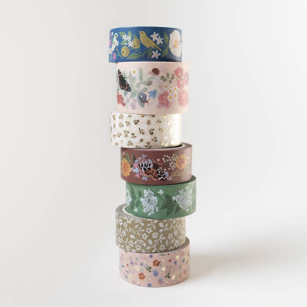Stack of colorful washi tape rolls with floral patterns on a white background