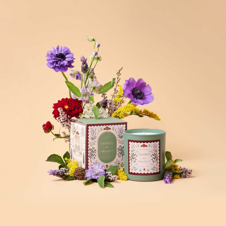 Candle and packaging with flowers on a beige background
