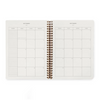 An open spiral-bound planner showing a September calendar layout with a weekly notes section on the left and a weekly grid on the right, photographed on a clean white background.