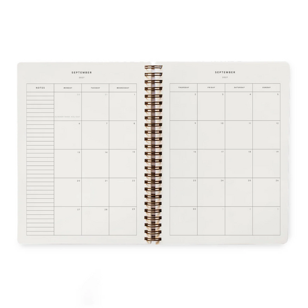 An open spiral-bound planner showing a September calendar layout with a weekly notes section on the left and a weekly grid on the right, photographed on a clean white background.