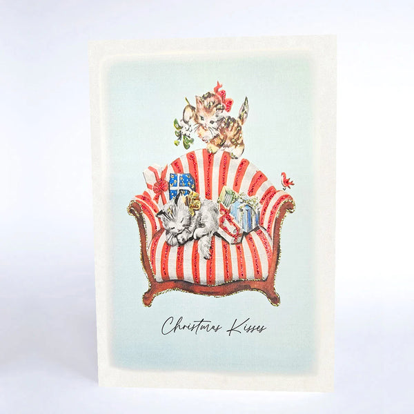Illustration of cats on a striped chair with 'Christmas Kisses' text on a light blue background