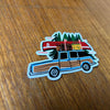 Sticker of a vintage station wagon with camping gear on a wooden surface