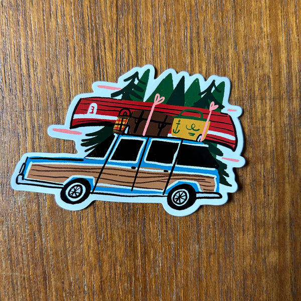 Sticker of a Woody Wagon with camping gear on a wooden surface