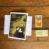 Father's Day card with a child and bird illustration on a wooden surface with stamps.