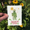 Card with illustration of a green man holding a sun, surrounded by flowers and leaves.