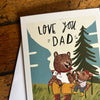 Greeting card with bear illustration and 'Love You Dad' text on a wooden surface