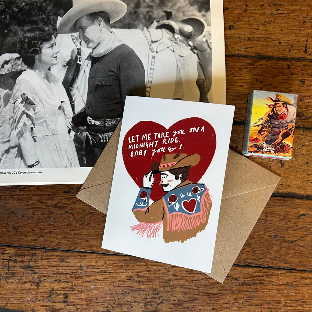 Card with cowboy and cowgirl illustration and text on a wooden surface