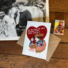Card with cowboy and cowgirl illustration and text on a wooden surface