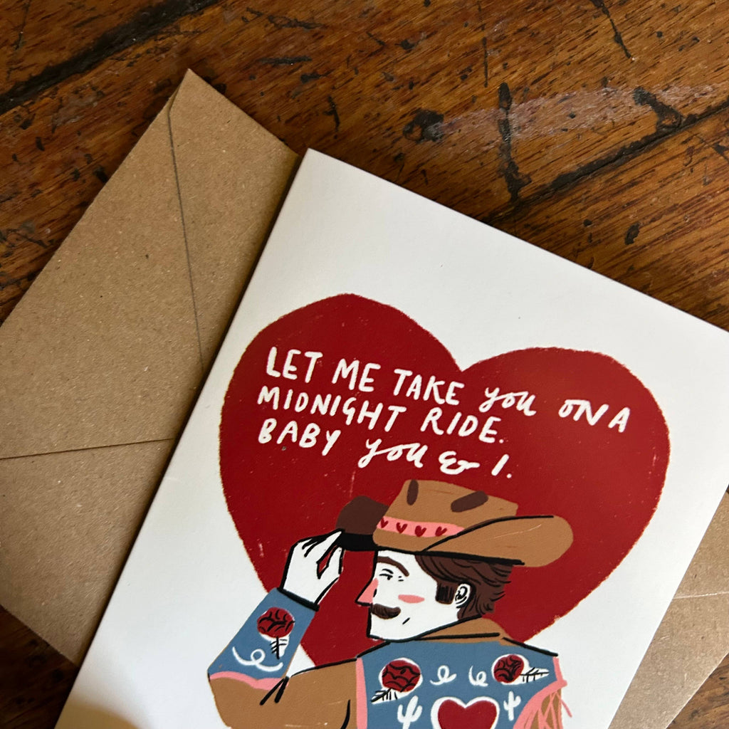 Card with cowboy illustration and heart-shaped message on a wooden surface
