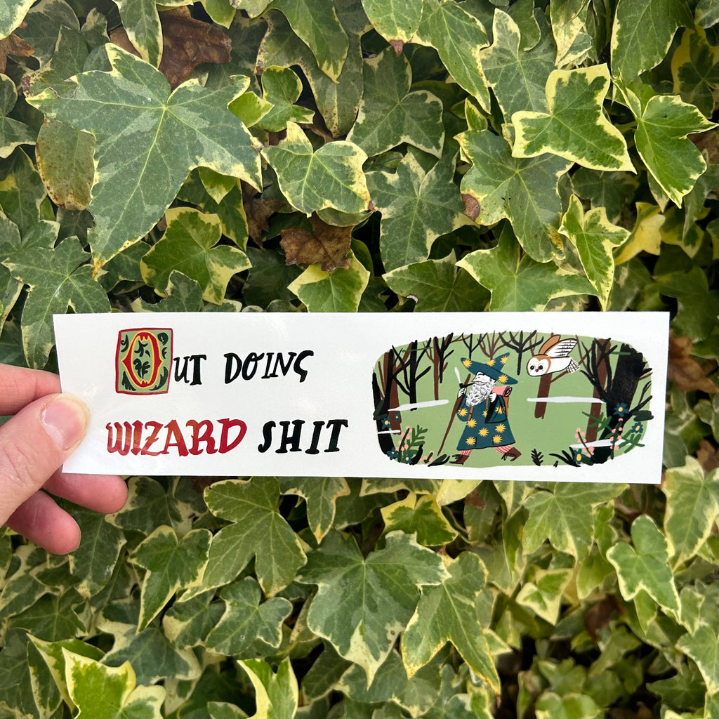 Hand holding a card with text and graphics against a leafy green background