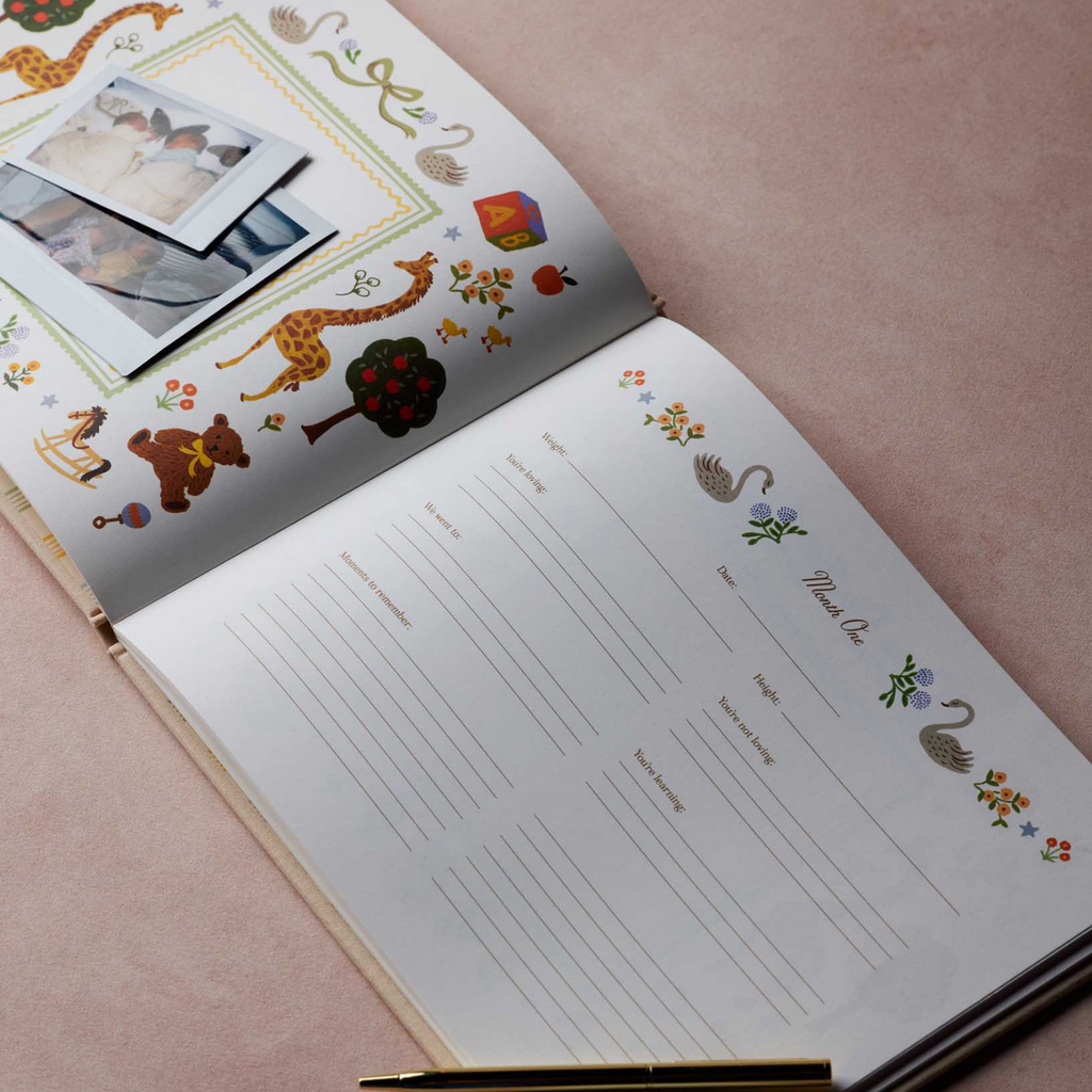 An open personalized children's photo album on a dusty pink background, featuring animal illustrations, a photo collage, writing lines, and a gold pen resting on the pages.
