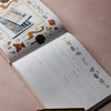 An open personalized children's photo album on a dusty pink background, featuring animal illustrations, a photo collage, writing lines, and a gold pen resting on the pages.