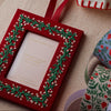 Red picture frame ornament with green embroidery on a beige surface