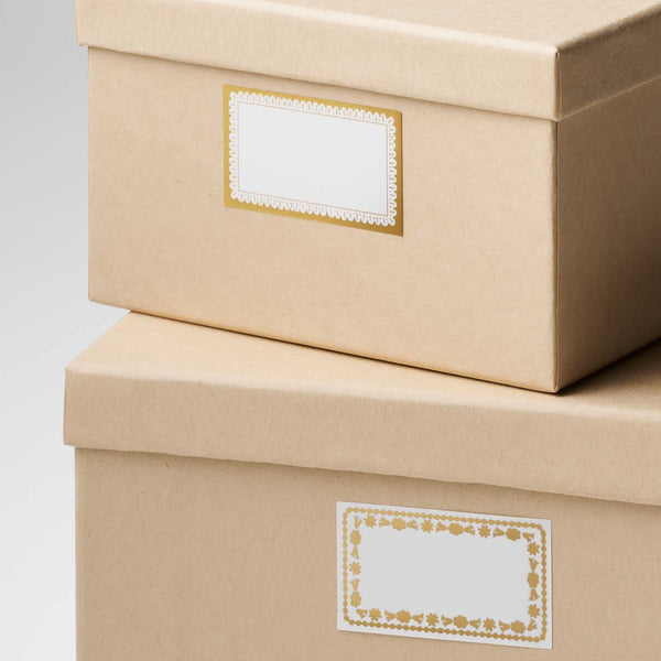 Two beige storage boxes with decorative labels on a light gray background