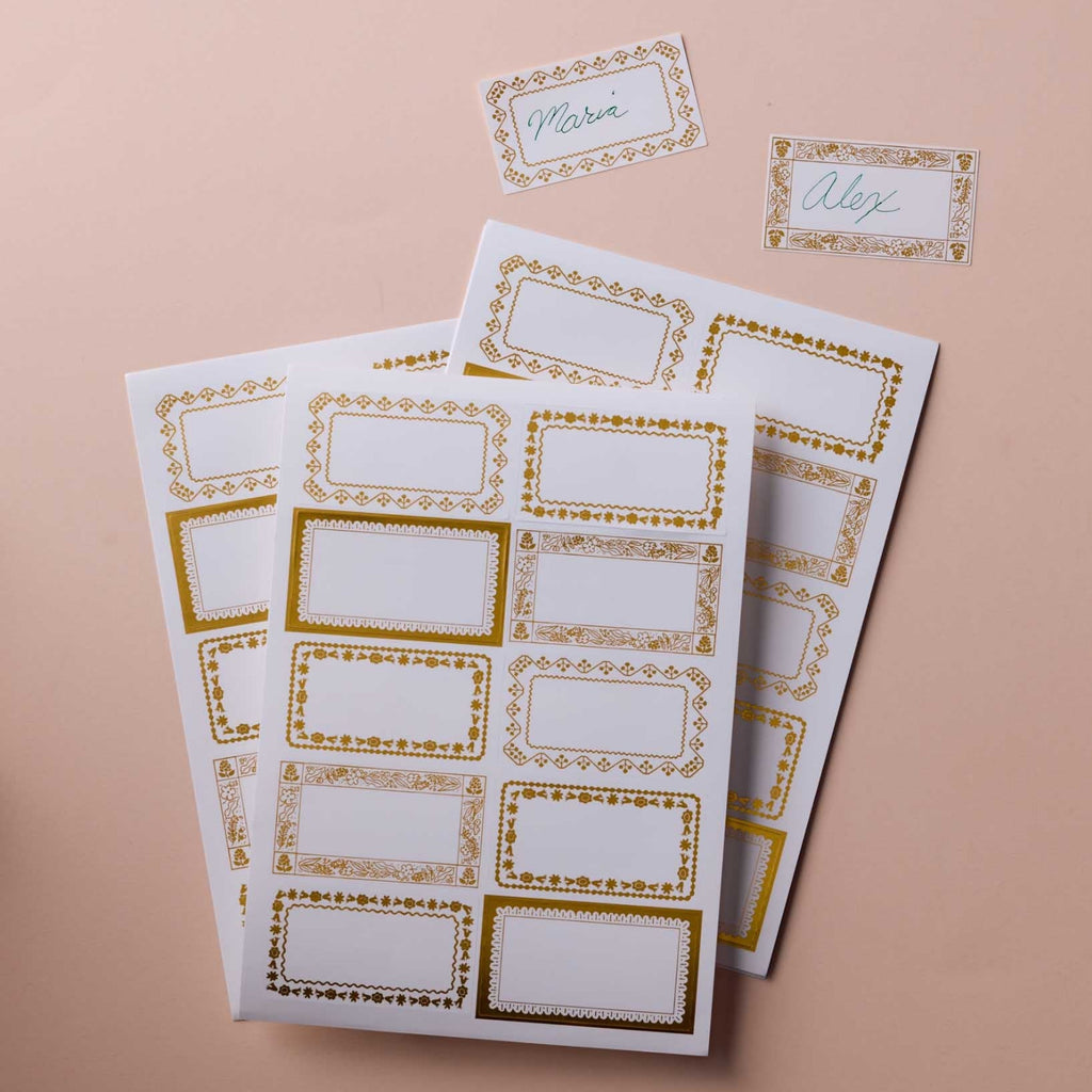 Two sheets of decorative name labels with gold borders on a beige background.