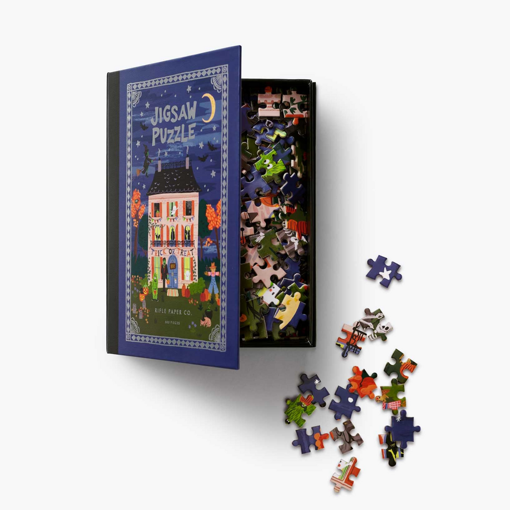 A jigsaw puzzle box shown open on a light gray background, with the illustrated cover visible on the left, loose puzzle pieces scattered on the right, and a smaller view of the packed interior in the center.