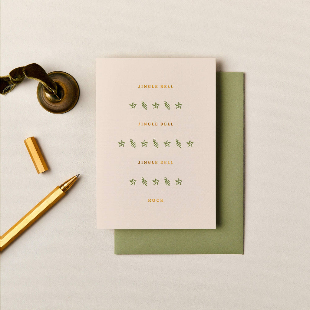 Cream A6 Christmas card with gold foil typography and green icons, paired with an olive green envelope.