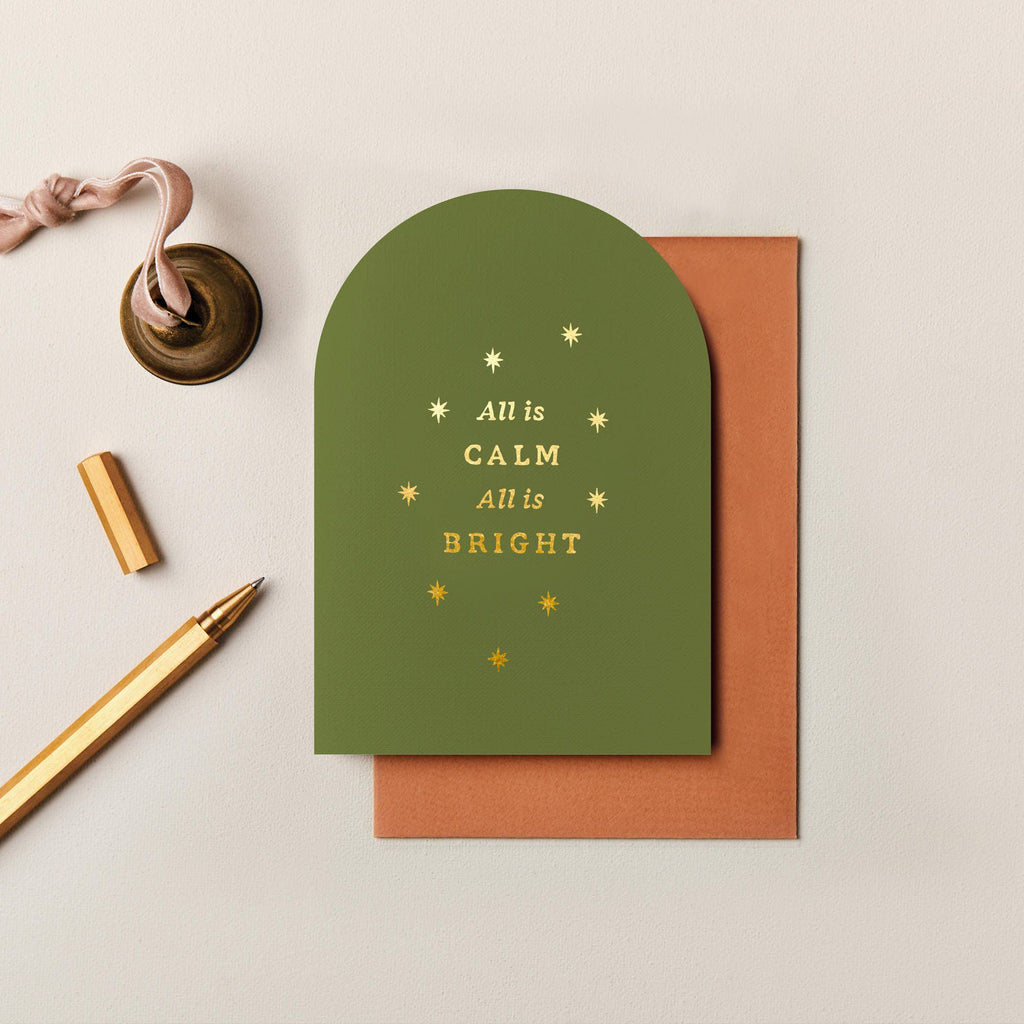 Olive green arched Christmas card with gold foil text and stars, textured cardstock, and a rust-colored envelope.