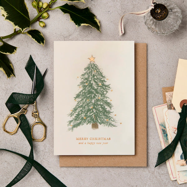 Christmas card with a tree design on a gray surface with decorative items.