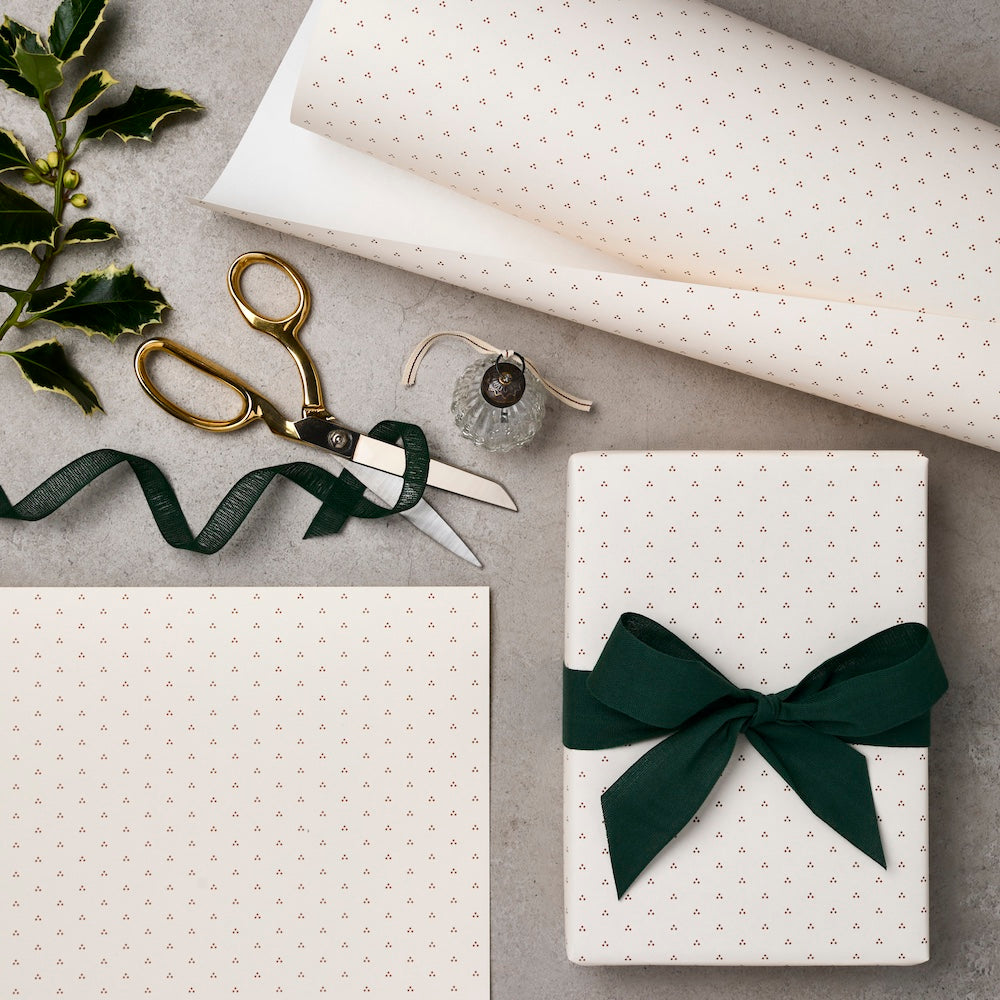 Gift box with green ribbon, scissors, and wrapping paper on a gray surface