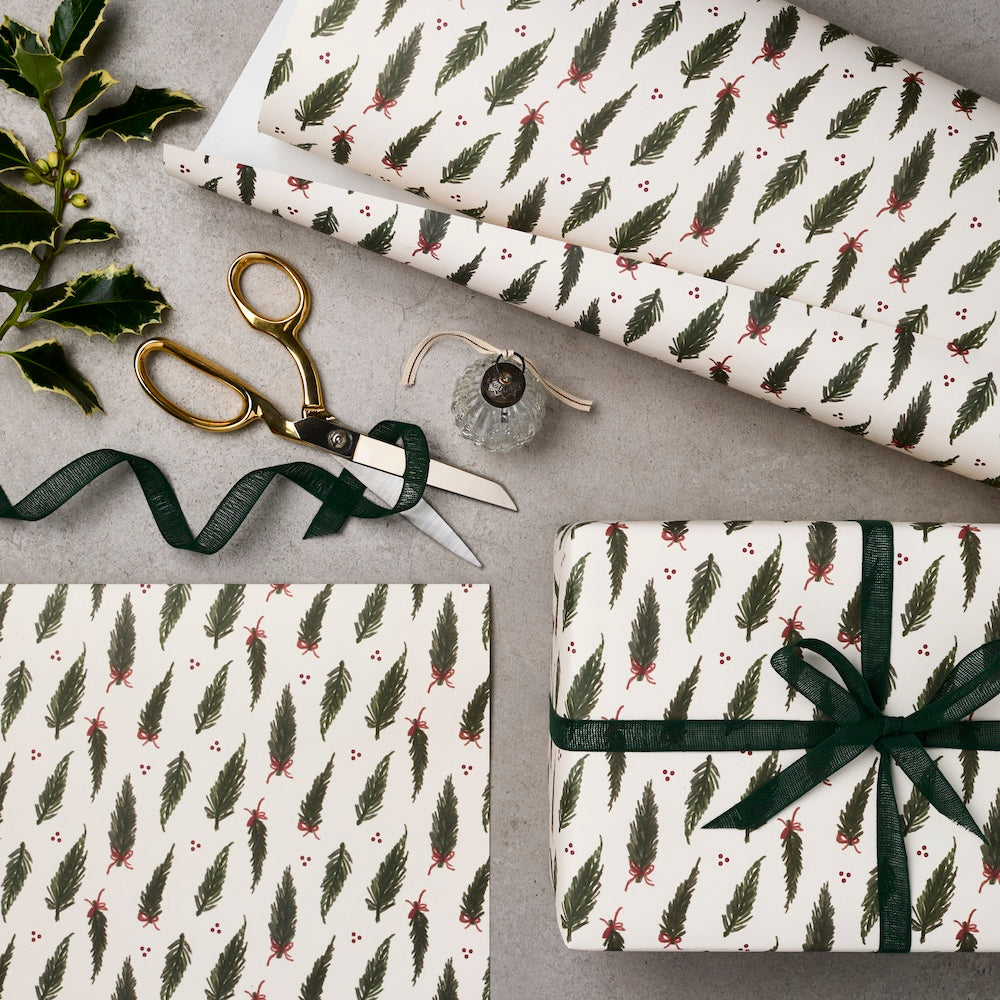 Gift wrap with feather pattern, scissors, and ribbons on a gray surface