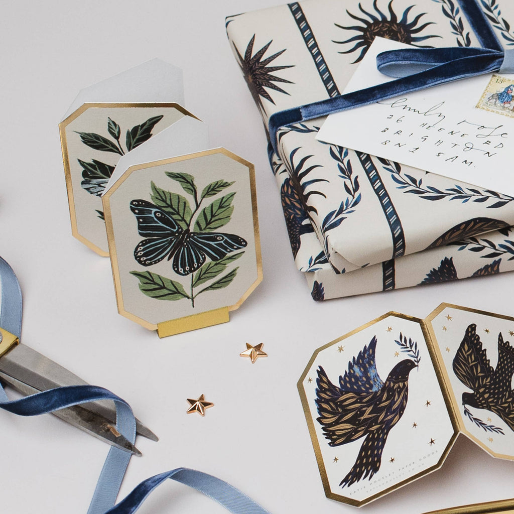 Decorative coasters with nature-themed designs on a white surface with gift wrap and scissors.