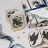 Decorative coasters with nature-themed designs on a white surface with gift wrap and scissors.