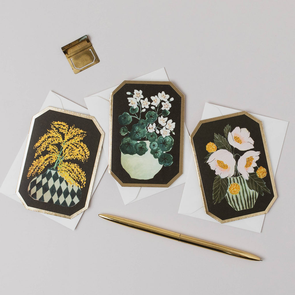Three floral embroidered cards on white paper with a gold pen and inkwell.